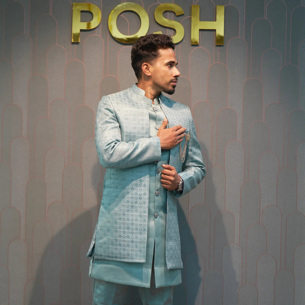 Man in a light blue suit standing in front of a 'POSH' branded wall.