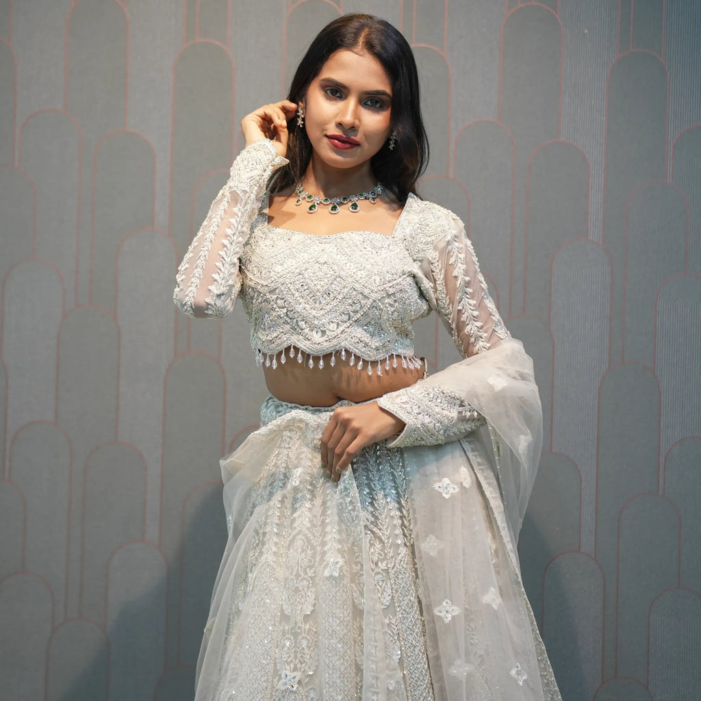 Woman in a white embroidered outfit standing in front of a 'POSH' branded backdrop