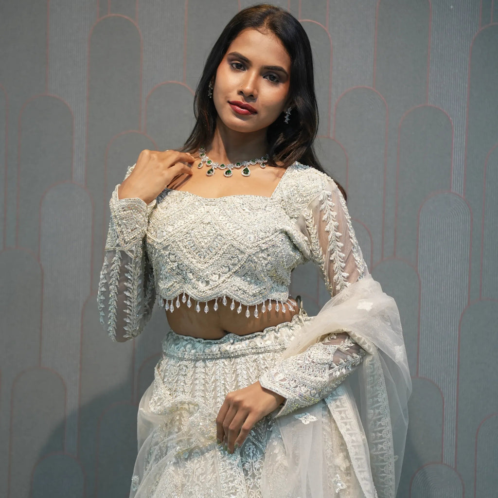 Woman wearing a light blue embroidered traditional outfit against a gray background