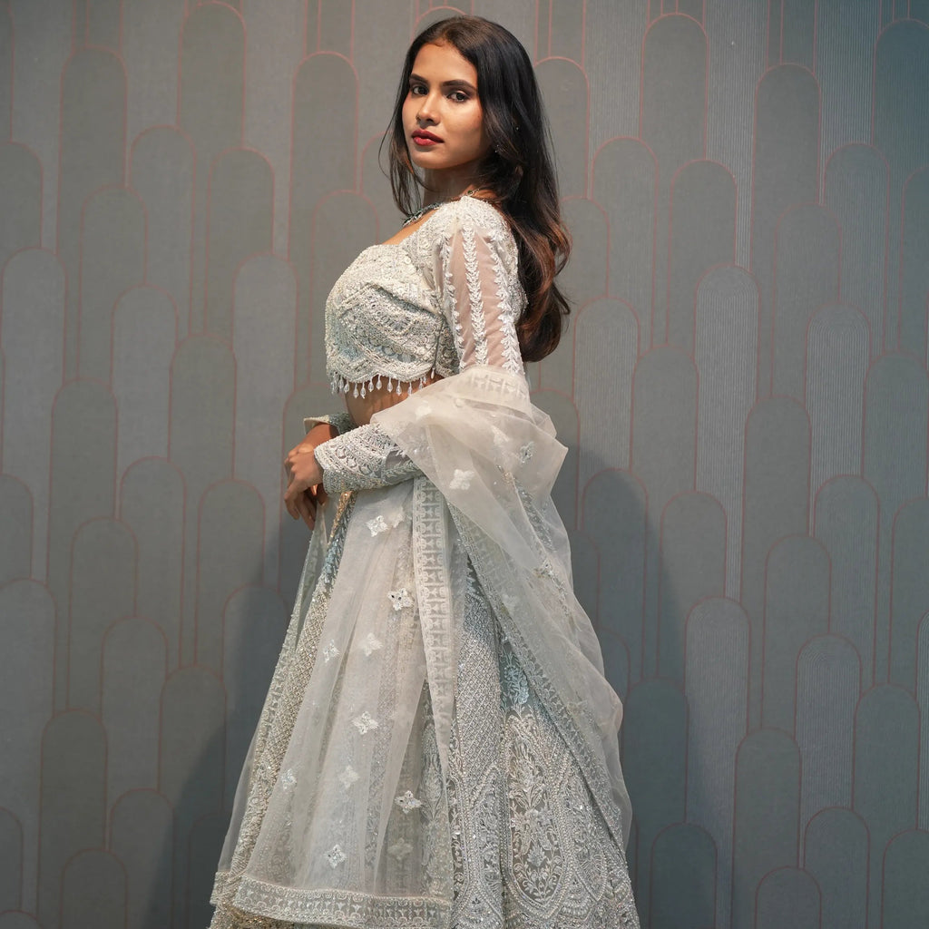 Woman in a light blue traditional outfit standing in front of a 'POSH' sign.