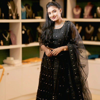 Woman in a black traditional outfit with jewelry in a store setting
